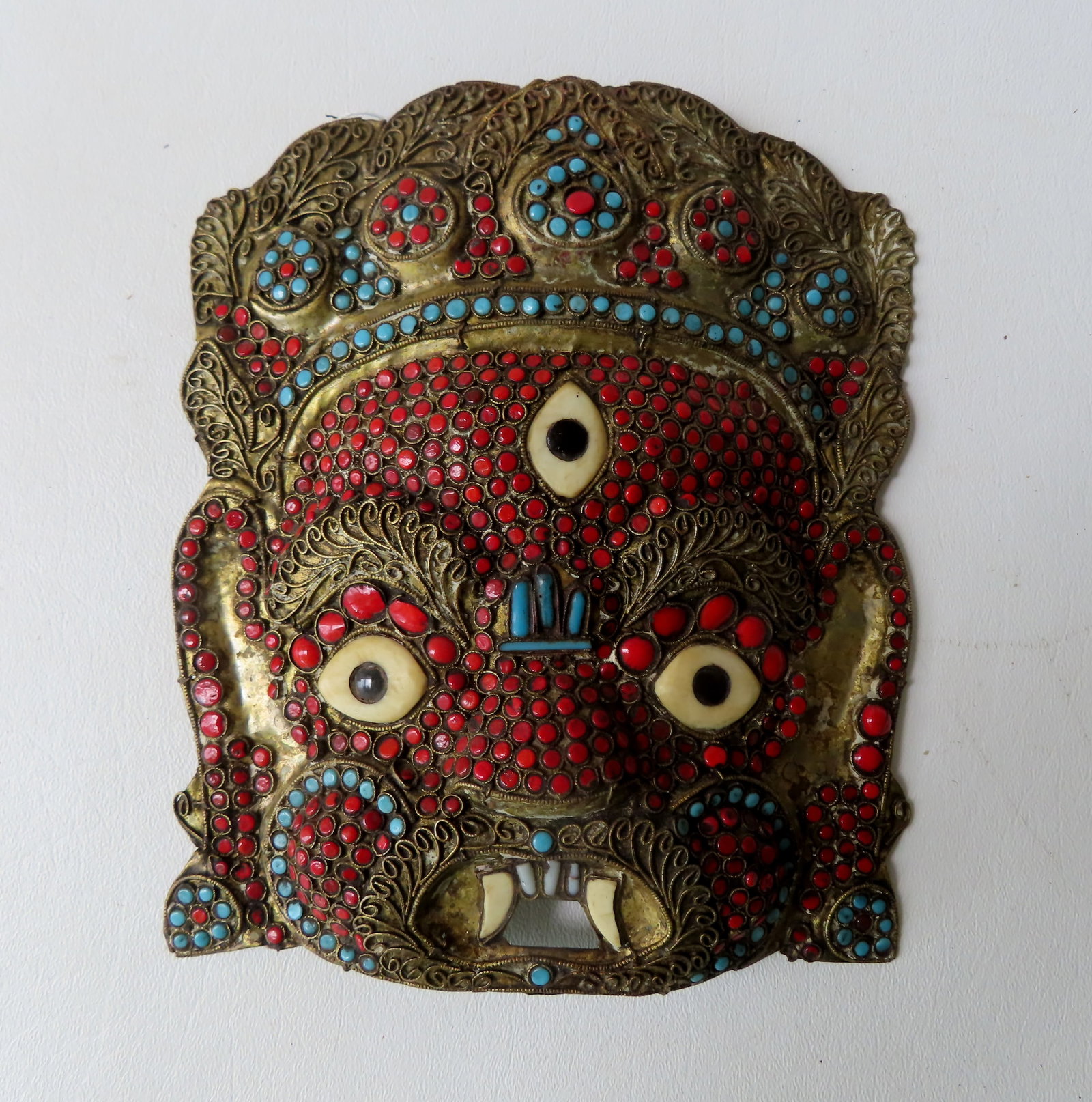 Tibetan Buddhist handmade Mahakala mask set with red coral, and turquoise stones. Note the third eye: Tibetan Buddhist handmade Mahakala mask set with red coral, and turquoise stones. Note the third eye on the forehead. It measures 8” H x 6 1/2”W. Very good condition.