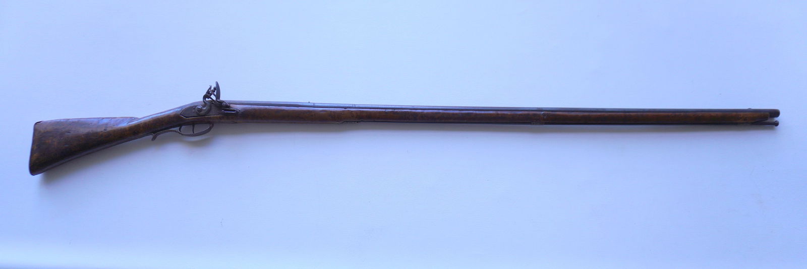 An original 18th century American flintlock musket with full tiger maple stock, imported lock plate: An original 18th century American flintlock musket with full tiger maple stock, imported lock plate signed "London Warranted", brass butt plate, and having an inlaid dragon ornament on the reverse sid