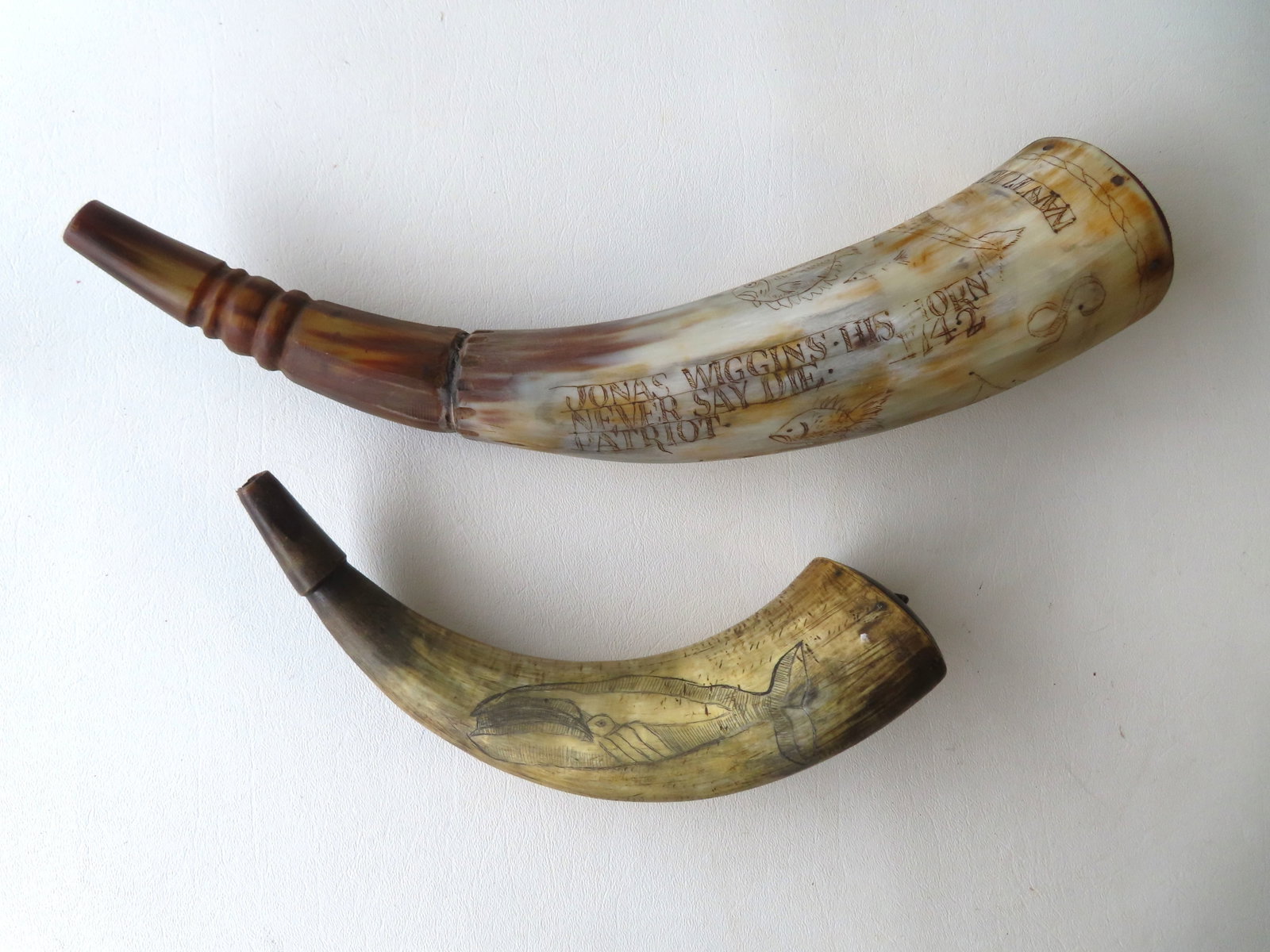 Two scrimshaw powder horns. The largest measures 14"L and is a late 20th century copy of an 18th: Two scrimshaw powder horns. The largest measures 14"L and is a late 20th century copy of an 18th century Nantucket powder horn; the small horn is 19th century but the unsure about the scrimshaw but ma