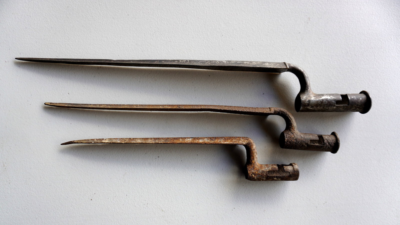 Three early socket bayonets including: A signed "Osborn & Gunby" bayonet, probably for a Brown Bess,: Three early socket bayonets including: A signed "Osborn & Gunby" bayonet, probably for a Brown Bess, having a tapered flat top over double grooved edge, early 19th century - no scabbard but in good co