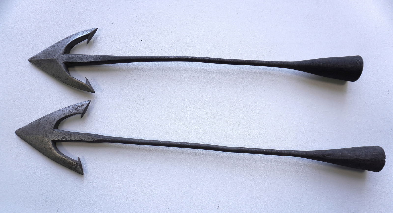 Two heavy wrought iron whaling harpoons with applied hand forged iron cones at base for attaching to: Two heavy wrought iron whaling harpoons with applied hand forged iron cones at base for attaching to wooden shaft - one impressed "1806" and with "BH" monogram within heart. Unsure of age but probably