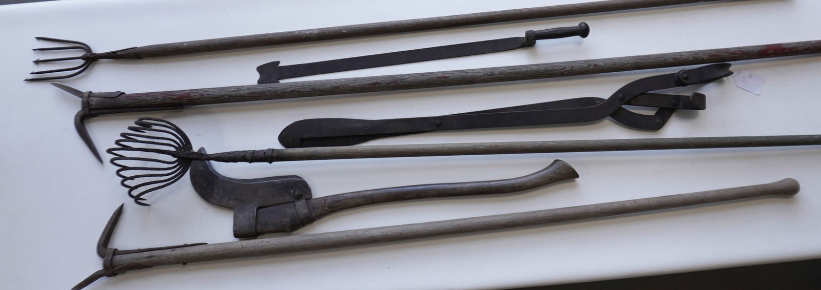 Seven early farm and nautical tools including: A hand forged iron clam rake, 19th century -: Seven early farm and nautical tools including: A hand forged iron clam rake, 19th century - extensive pitting; a signed Collins brush cutter; eel spear, mid 20th century; 2 logging pikes, late 19th ce