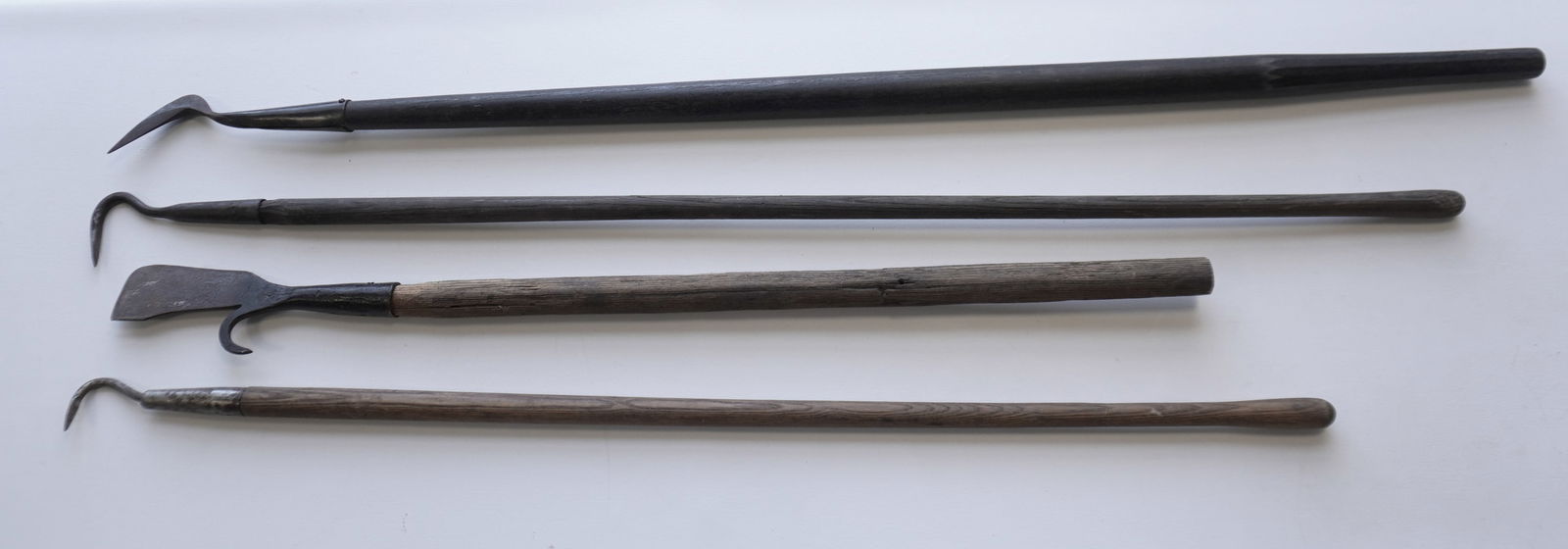Grouping of 4 iron whaling tools with long wooden handles, including: 2 gaffing hooks (one 19th: Grouping of 4 iron whaling tools with long wooden handles, including: 2 gaffing hooks (one 19th century, the other a little later), 1 blubber spade with peeling hook - mid 19th century, and a hook (th