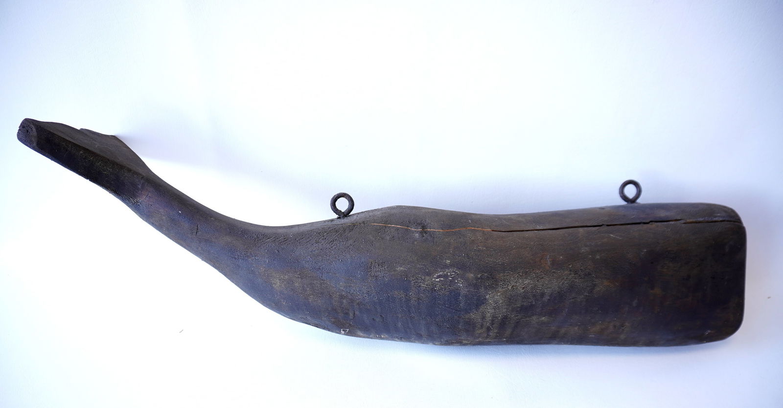 Full body carved wooden hanging whale with turned tail, in a black stain, probably 3rd quarter 20th: Full body carved wooden hanging whale with turned tail, in a black stain, probably 3rd quarter 20th century. Unknown carver. Includes mounting brackets for hanging from ceiling. Age crack, otherwise g