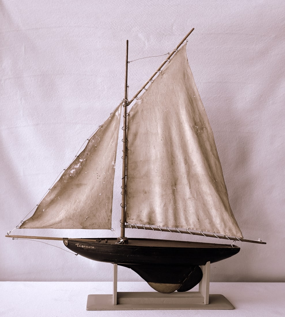 A handmade sailboat model in original paint, laminated hull construction, original sails with holes: A handmade sailboat model in original paint, laminated hull construction, original sails with holes and taped repairs, but overall good condition, late 19th to early 20th century. Measures approximate