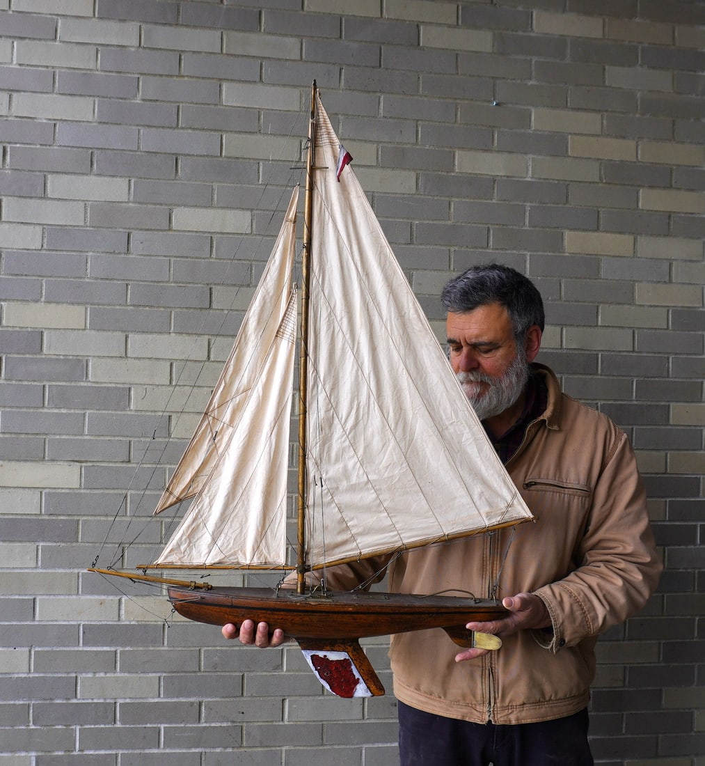 A fully rigged pond sailboat with original sails, working brass rudder, solid wooden hull, and: A fully rigged pond sailboat with original sails, working brass rudder, solid wooden hull, and weighted keel. The keel with losses to red paint, else very good condition, circa 1900. Measures 31"L x 6