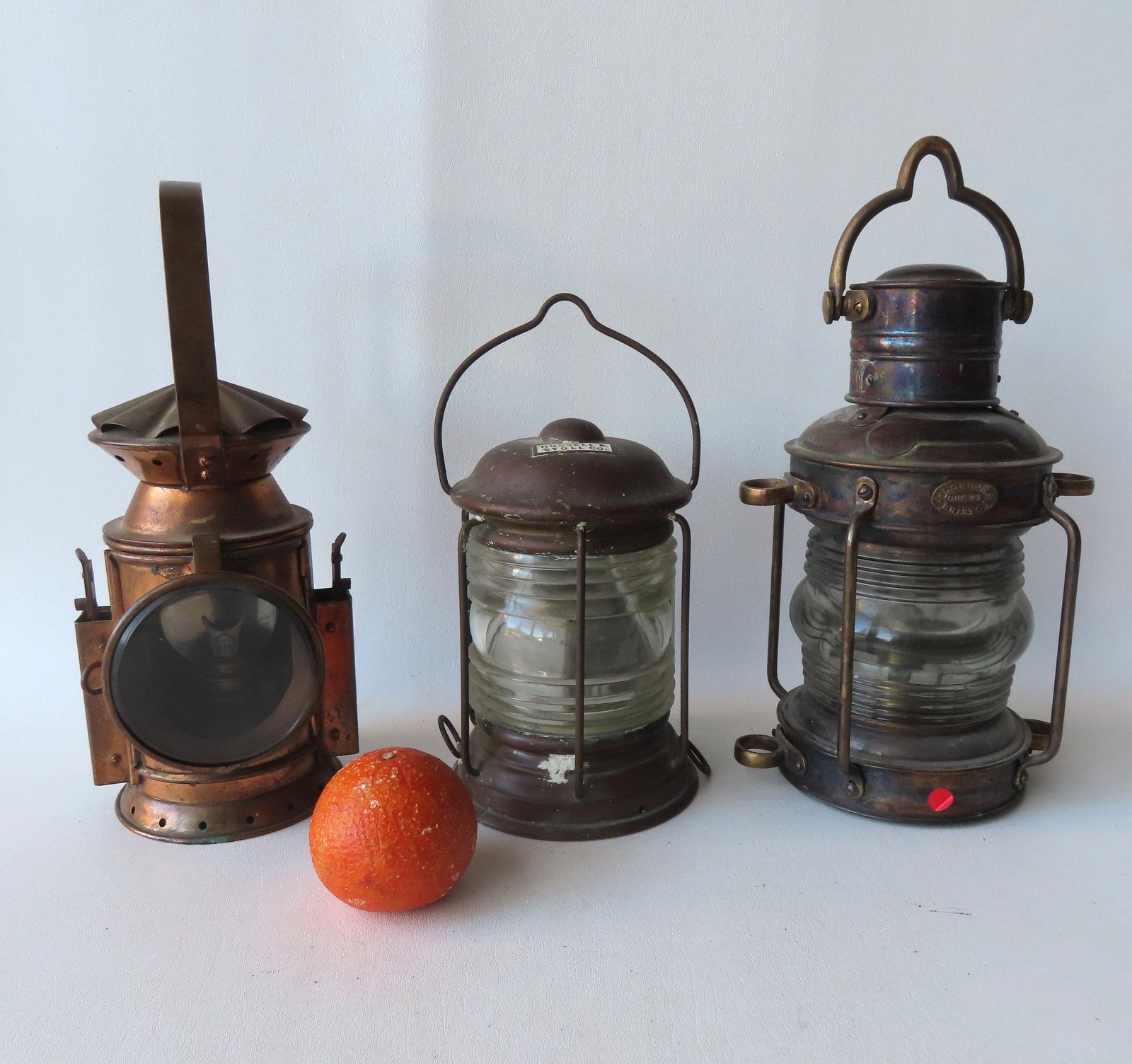 Three nautical related lanterns including: Copper lamp with colorless glass lens, signed Russell &: Three nautical related lanterns including: Copper lamp with colorless glass lens, signed Russell & Stoll Co. - with bracket and bale handle - missing oil lamp, otherwise good condition - 8"H x 6"W; an
