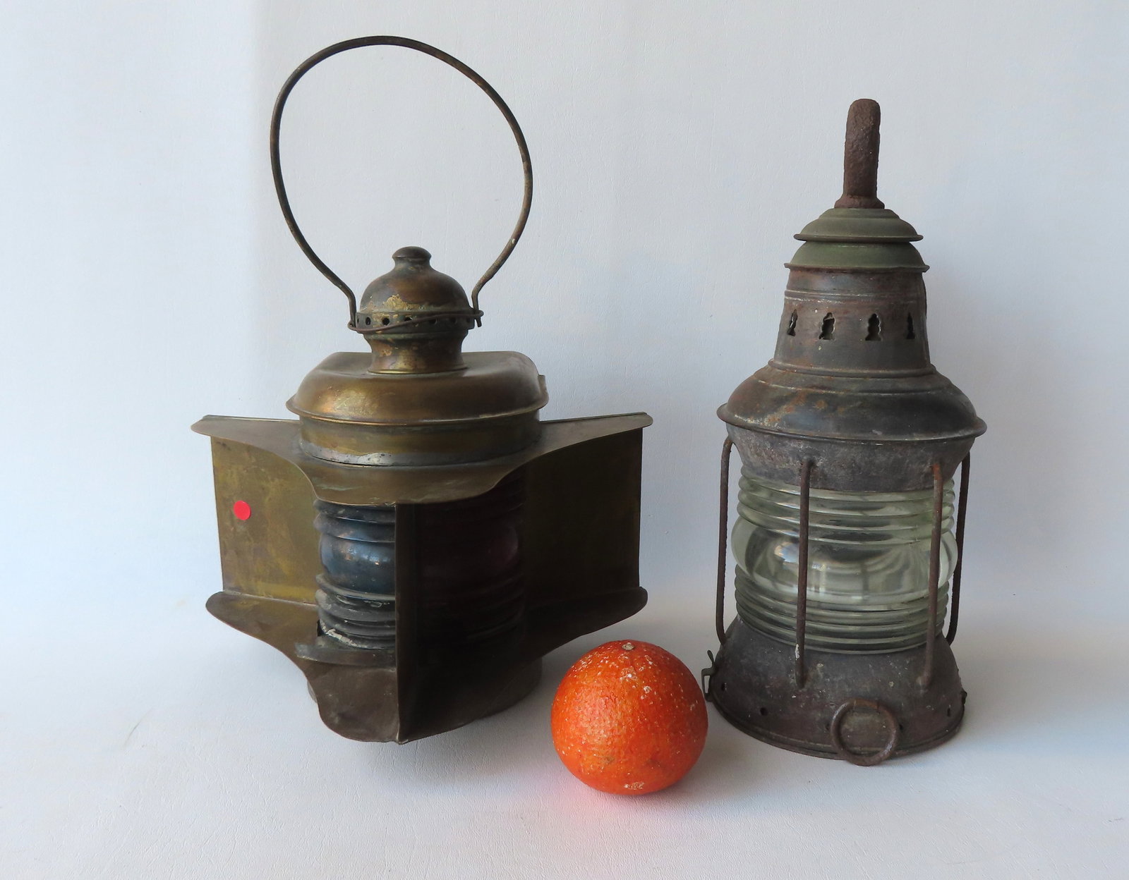 Two nautical oil lamps, late 19th century. The first with a wrought iron bracket for attaching to: Two nautical oil lamps, late 19th century. The first with a wrought iron bracket for attaching to wall or cabin, colorless lens, and missing interior oil burner - 13 1/4"H x 10"W; and a brass lantern 