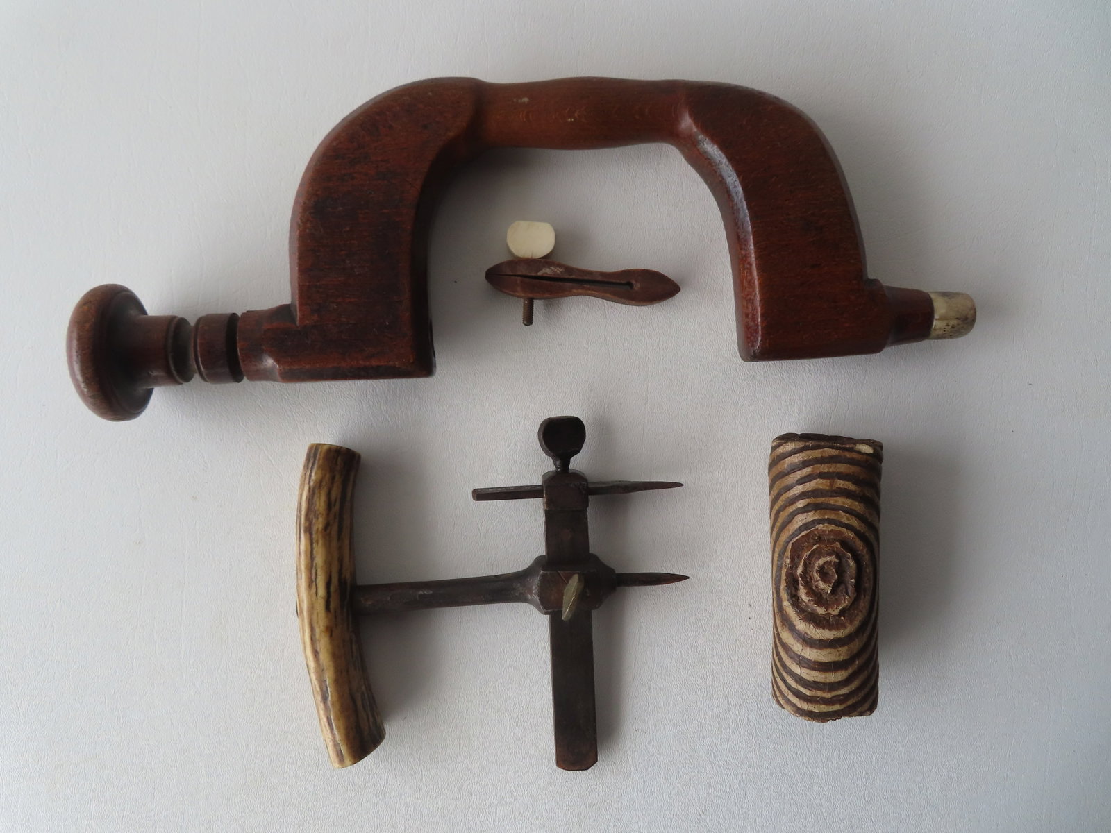 Four tradesman's tools including: An iron marking gauge with animal horn handle - appears to be hand: Four tradesman's tools including: An iron marking gauge with animal horn handle - appears to be hand forged - late 18th to early 19th century; small wooden clamp, a wooden hand brace signed "S"; and a