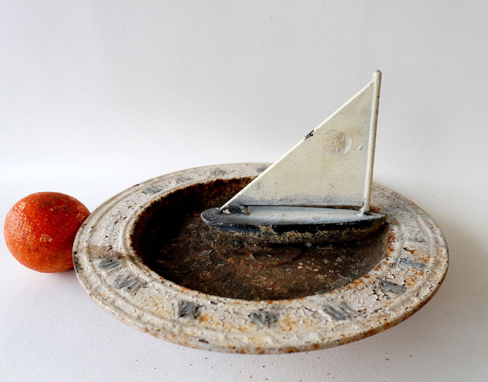 A vintage cast iron sundial and birdbath combination, with a sailboat shape gnomon, and signed on: A vintage cast iron sundial and birdbath combination, with a sailboat shape gnomon, and signed on base "The Mariner's Sundial". Layers of old crazed paint and some rust otherwise good condition. Measu