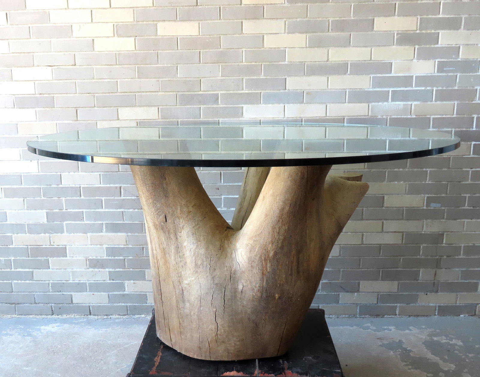 A custom made mid-century rustic kitchen table having a glass top (5' diameter x 1" thick) mounted: A custom made mid-century rustic kitchen table having a glass top (5' diameter x 1" thick) mounted on a real tree trunk base (31 1/2"H x 38" widest point) - total table height 32 1/2"H. Tiny chip on e