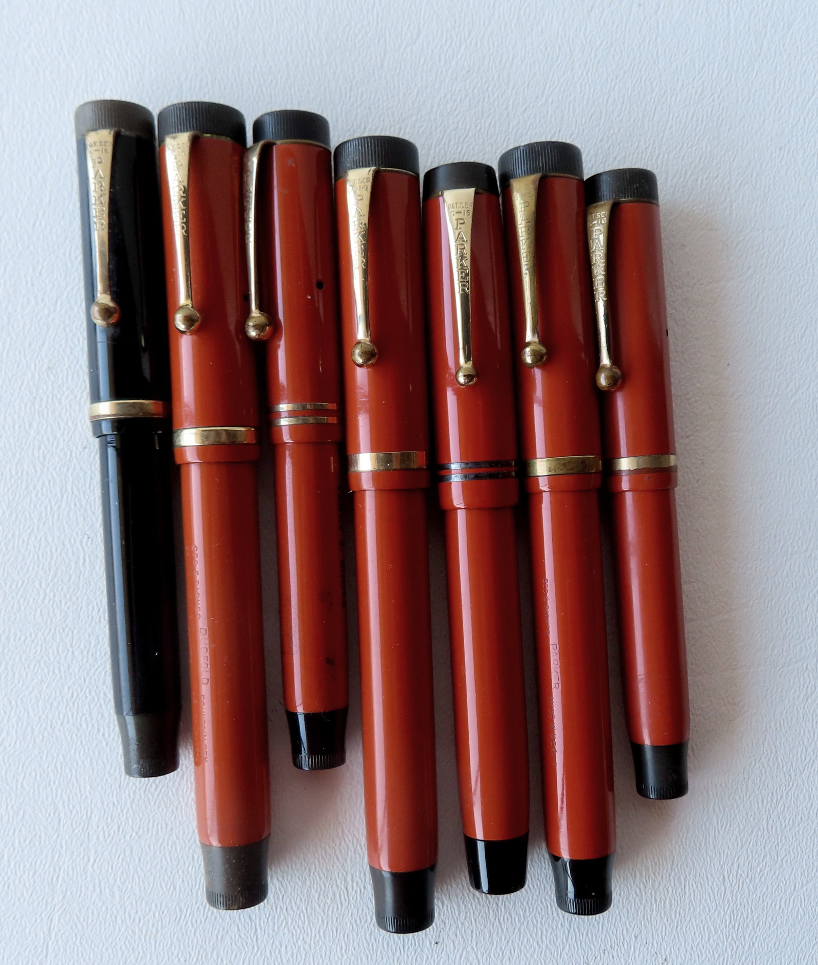 Grouping of 7 Parker fountain pens including: Orange Duofold Jr. "Lucky Curve" and also marked with: Grouping of 7 Parker fountain pens including: Orange Duofold Jr. "Lucky Curve" and also marked with original owner's name "Yancy J. Rooks"; black Parker Duofold Jr. "Lucky Curve; 2 orange Parker Duofo