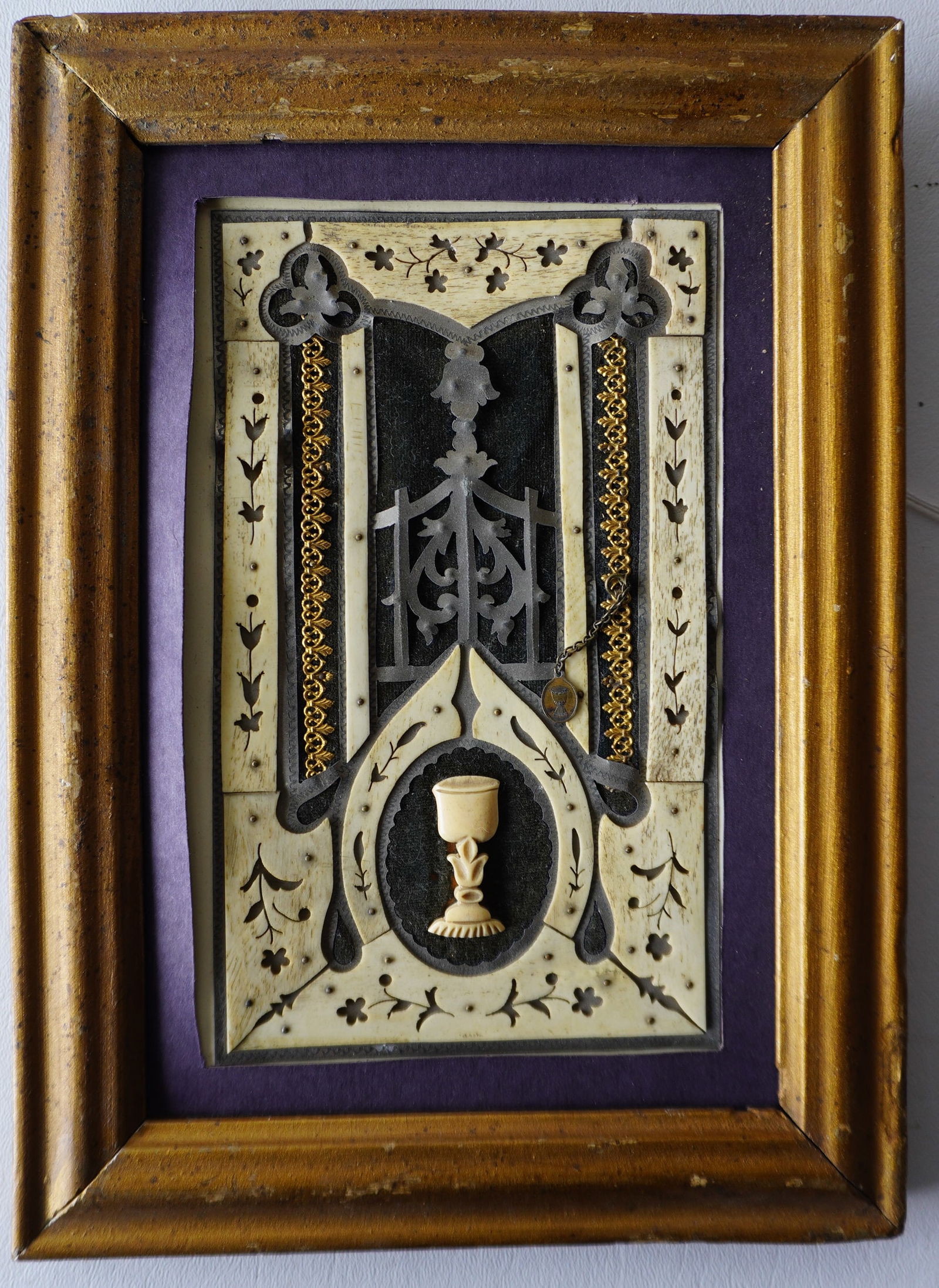 A framed mixed media religious representation of an alter with chalice, constructed of bone and: A framed mixed media religious representation of an alter with chalice, constructed of bone and various metals, and having a tiny gold religious medallion attached to chain, 19th century. Good conditi