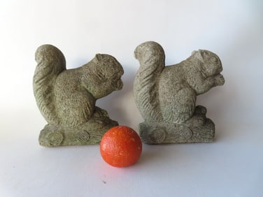 Two life size concrete squirrel ornaments for the garden, each eating nuts perched on logs, mid 20th