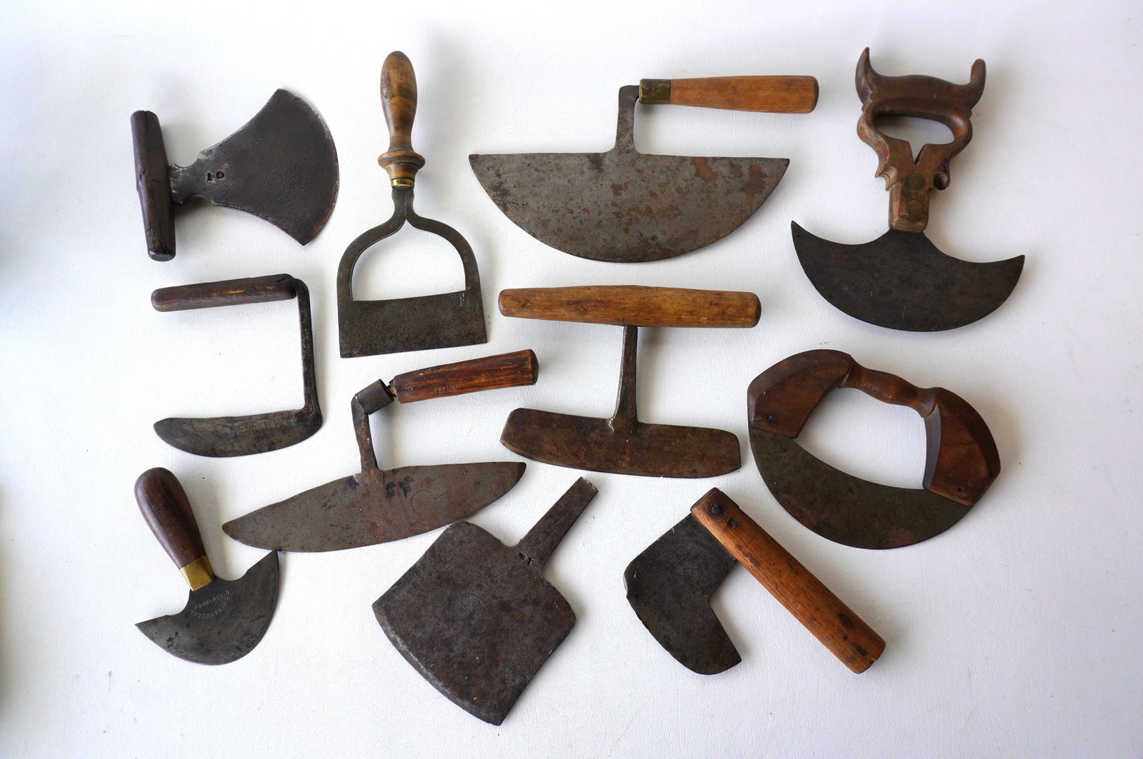 A grouping of 11 mostly hand forged iron food choppers with wooden handles, several signed, early to (1 of 15)