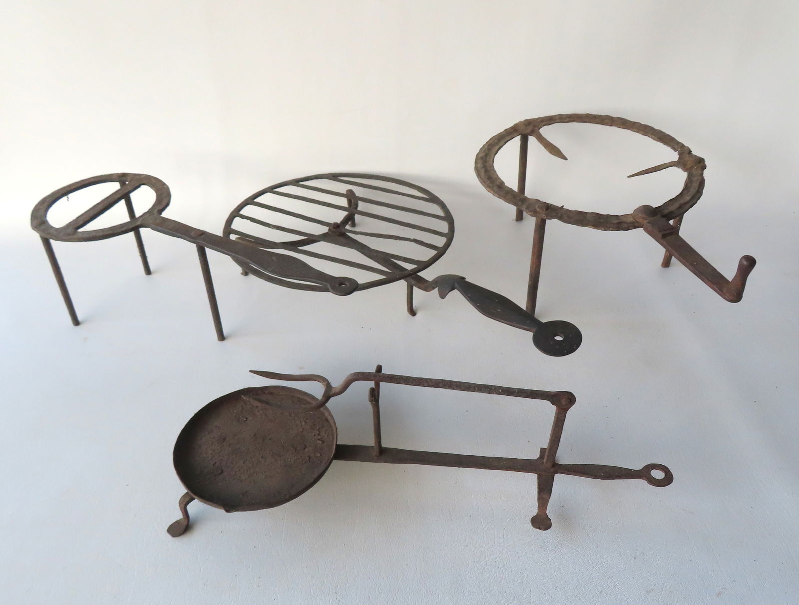 Grouping of 4 hand forged iron hearth items including 2 footed trivets, a revolving toaster, and an (1 of 16)
