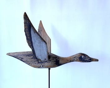 A hand carved folk art wooden flying duck weathervane, traces of original paint, screw eyes, and