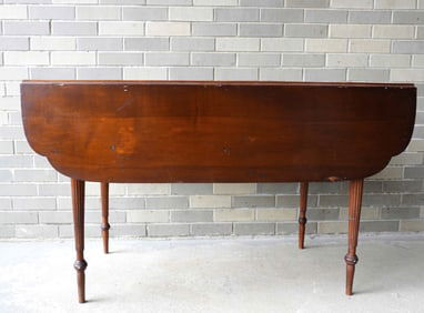 A Sheraton drop leaf table with short shaped drop leaves, similar to a small harvest table - appears