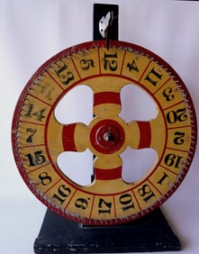 A colorful double sided carnival gaming wheel in original paint, and mounted on original table top
