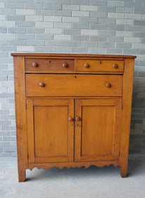 A clean pine jelly cupboard having 2 short drawers over 1 long drawer over 2 paneled doors on cutout