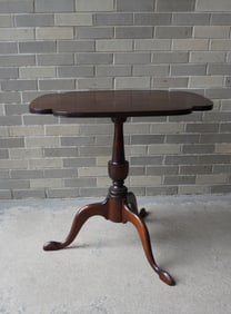 A mahogany tilt-top candlestand with snake feet, urn shaped pedestal and shaped top with beaded