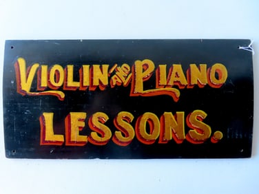 A vintage wooden sign "VIOLIN AND PIANO LESSONS.". The shadow lettering in original gold and red