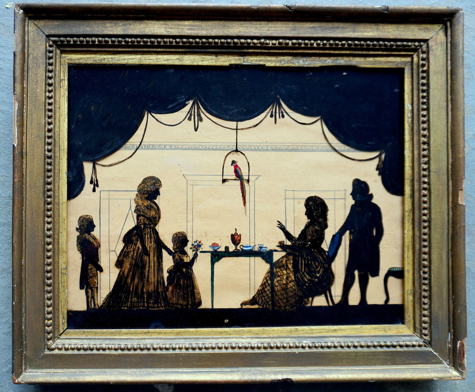 A framed reverse painted family silhouette on glass depicting a lady seated at a Queen Ann tea table (1 of 6)