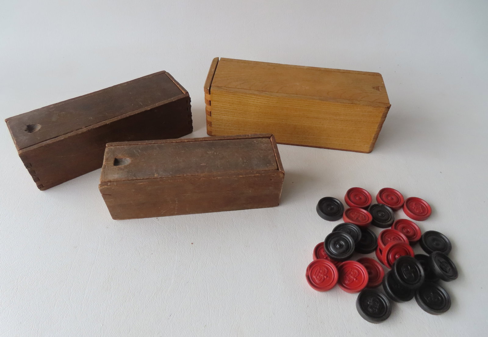 Three slide lid boxes containing sets of vintage dominoes in bone and ebony, together with a: Three slide lid boxes containing sets of vintage dominoes in bone and ebony, together with a complete set of gutta percha checkers, all 19th century and in good condition. The largest box measures 8"L