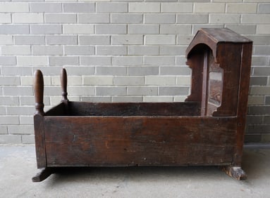 An early primitive hooded cradle with a paneled and chamfered back, early 18th century. Typical use