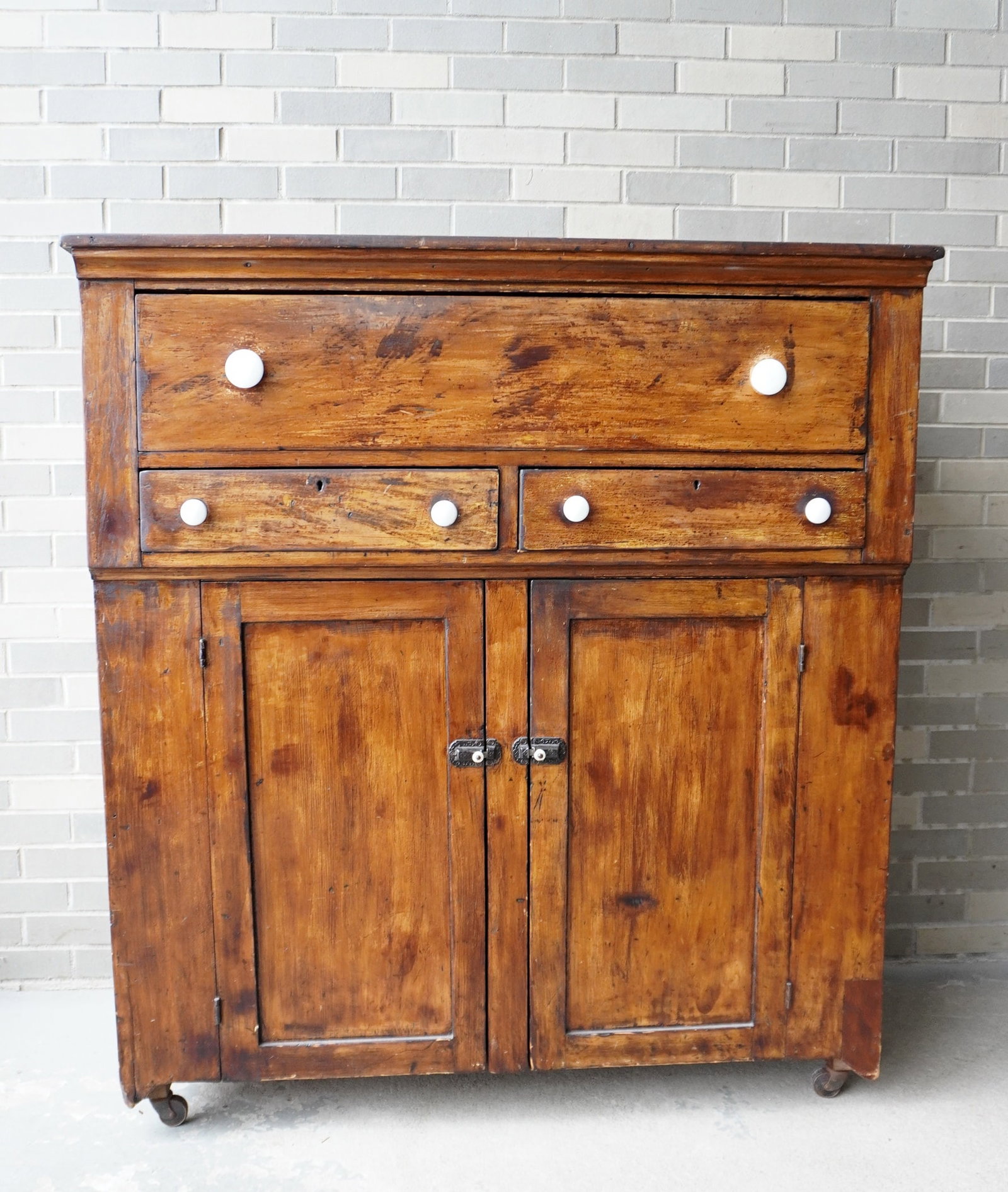 A jelly cupboard having 1 deep drawer over 2 side-by-side drawers over 2 paneled doors on cutout: A jelly cupboard having 1 deep drawer over 2 side-by-side drawers over 2 paneled doors on cutout base. Replaced porcelain pulls, small repair to right front foot, and cupboard has been stripped down t