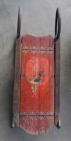 A stenciled and hand painted child's sled featuring a painting of a bird on sprig on the center of