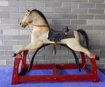 A dapple gray hobby horse in original paint, mounted on rocking platform in original red paint with