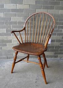 Bow-back Windsor arm chair in natural finish, having a 9 spindle back, saddle seat, splayed arms and