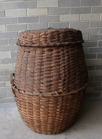 An unusually large covered feather basket with wooden handles applied to center horizontal woven