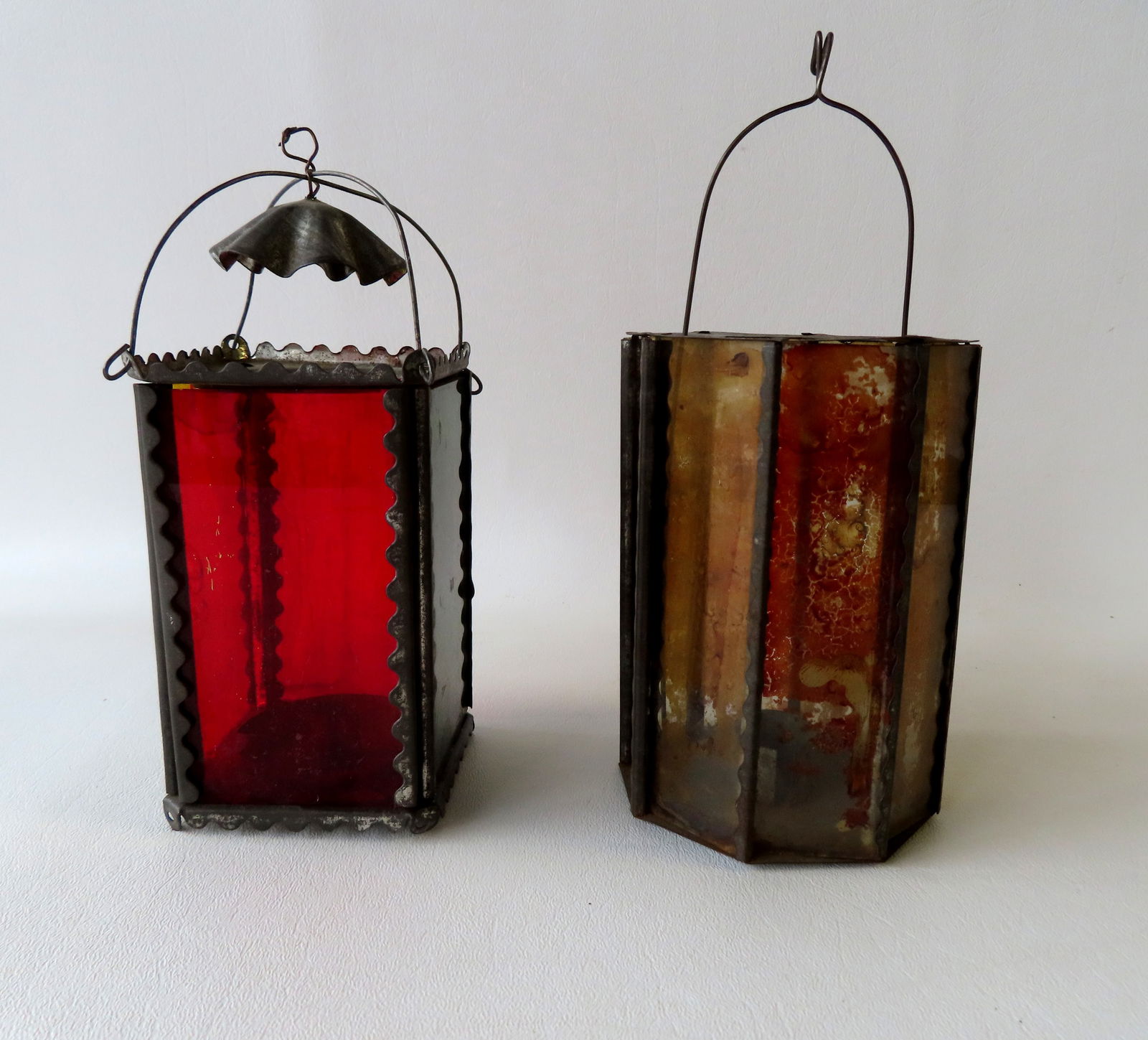 Two Christmas candle lanterns/holders, late 19th century. The first with octagonal glass reverse: Two Christmas candle lanterns/holders, late 19th century. The first with octagonal glass reverse painted sides and original tin hanger that attaches to candle font below - 8"H to top of hanger - some