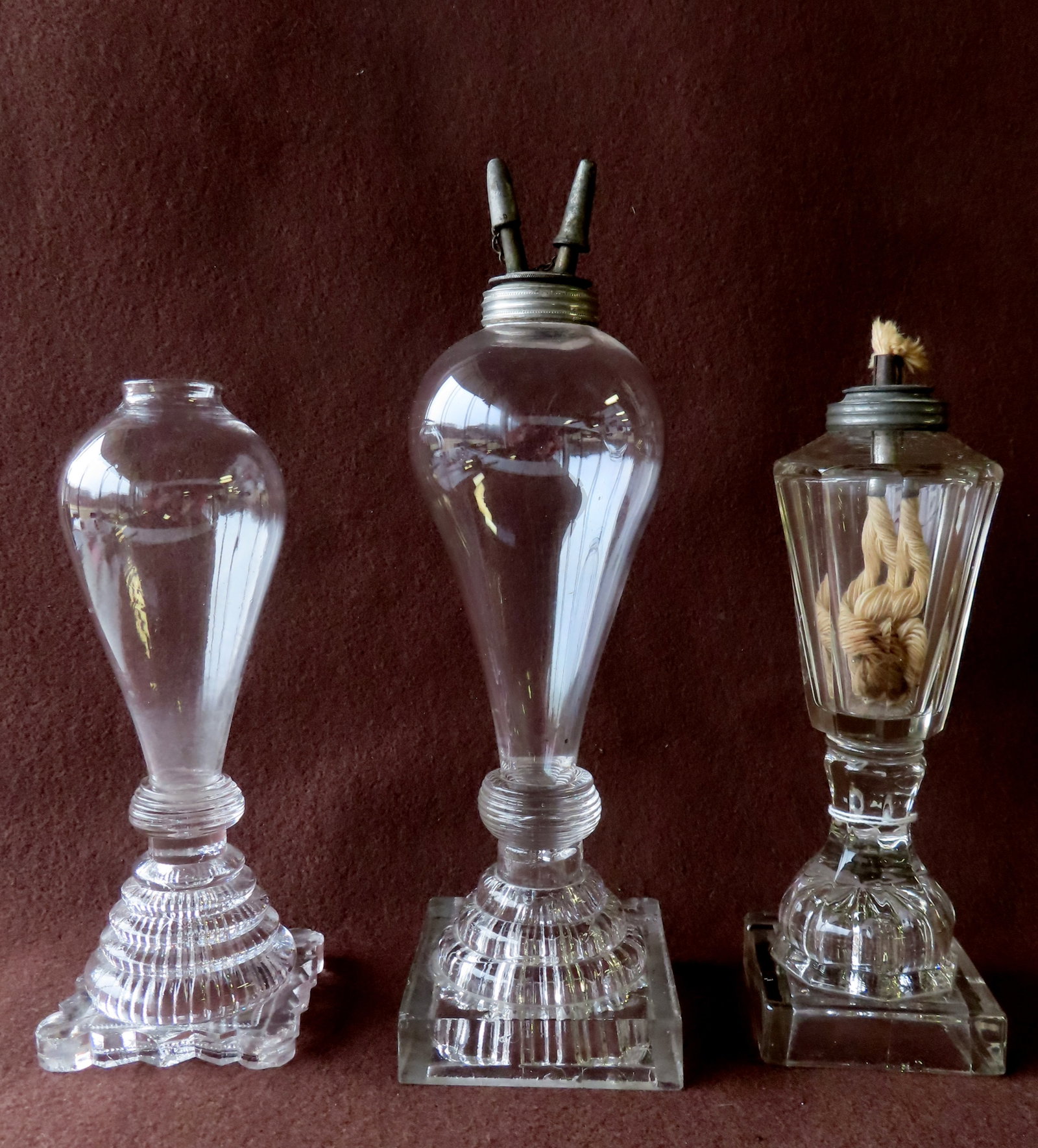 Three whale oil lamps, early 19th century. The first with bulb shaped blown font with pewter burner: Three whale oil lamps, early 19th century. The first with bulb shaped blown font with pewter burner mounted on pressed glass Waterfall base -slight roughness on edge of base, overall very good conditi