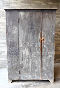 A primitive single door cupboard on cutout base, with layers of old paint including green (see