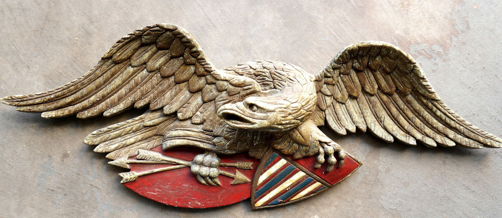 A large carved wooden spread wing eagle holding arrows in one talon and an American shield in the (1 of 9)