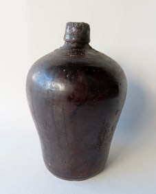 A stoneware jug with rounded and tapered sides, applied tooled handle, Albany glaze, marked "D.