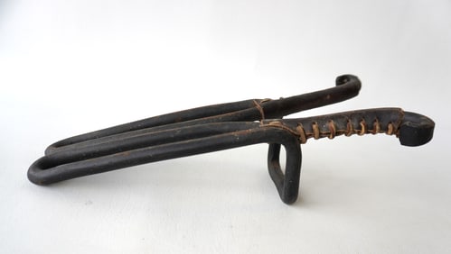 An unusual cast iron bootjack with original leather wrapped terminals to protect boots when being