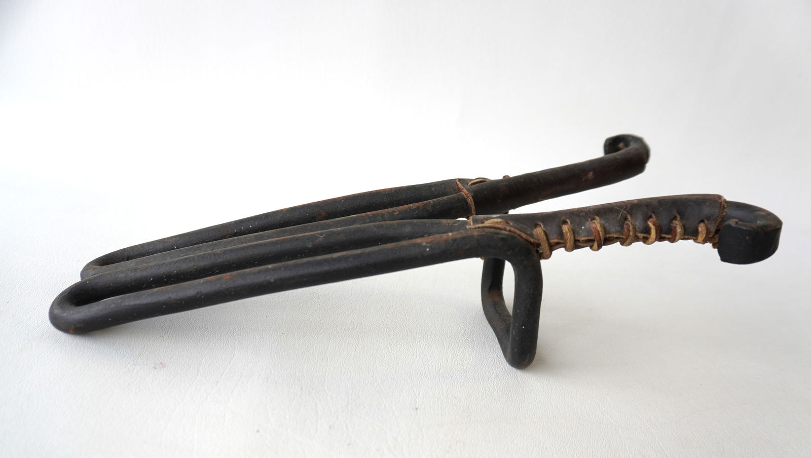 An unusual cast iron bootjack with original leather wrapped terminals to protect boots when being (1 of 6)