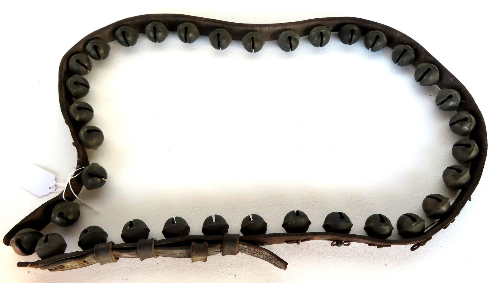 A set of brass sleigh bells with original leather strap - missing buckle, else good condition, 19th: A set of brass sleigh bells with original leather strap - missing buckle, else good condition, 19th century - measures 55"L.