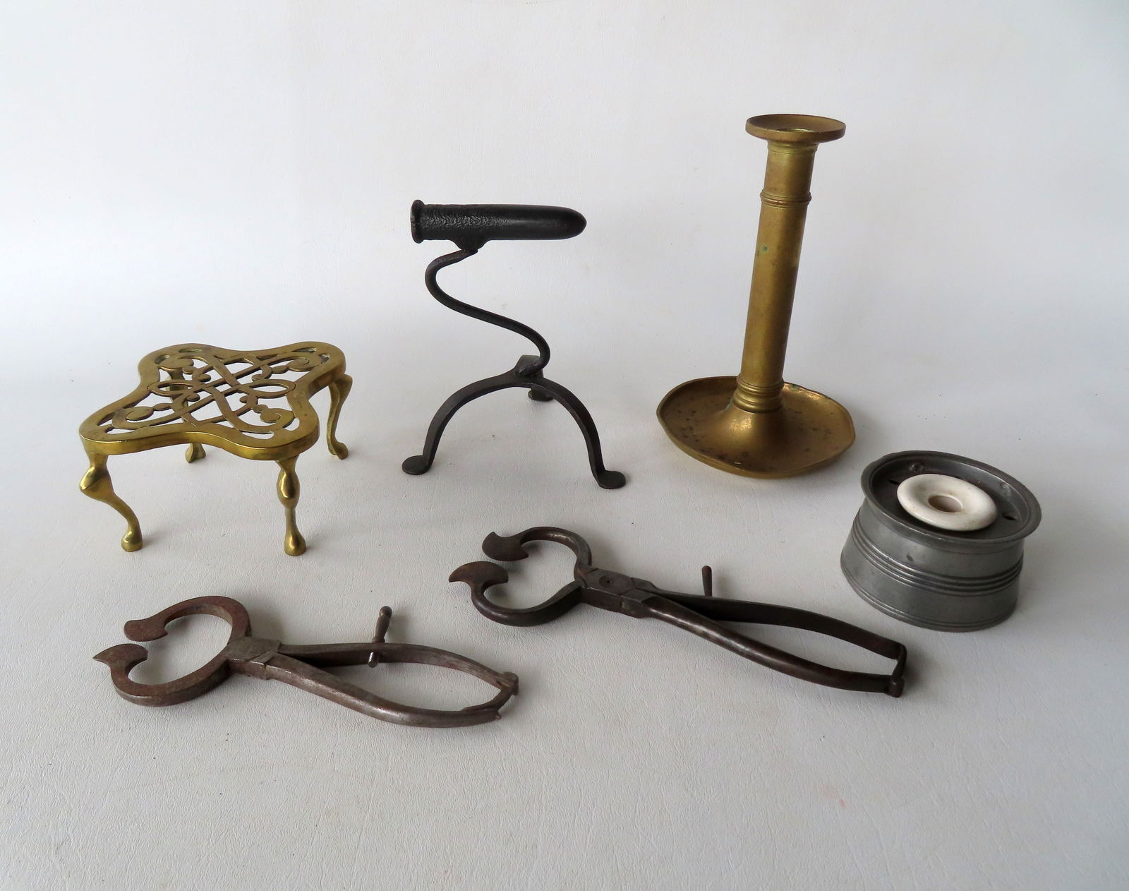 A grouping of country collectibles including: A small open work brass trivet, 2 iron sugar cutters,: A grouping of country collectibles including: A small open work brass trivet, 2 iron sugar cutters, an early brass candlestick (missing pushup lever on column), a pewter inkwell with original white po
