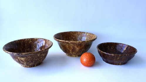 Three Bennington mixing bowls on footed bases, 19th century. One with glazing chip on the inside of