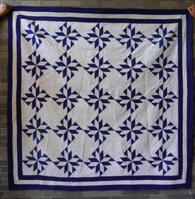 A blue and white patchwork quilt in pinwheel pattern with triple linear border, all hand sewn, late
