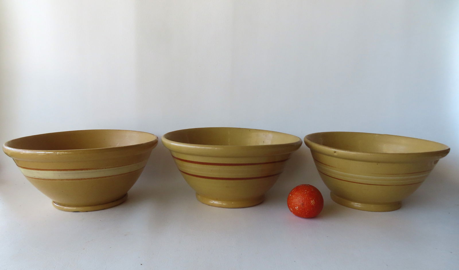 Three large banded yellowware mixing bowls with rolled rims on footed bases, 19th century. Each (1 of 16)