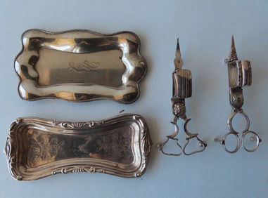 Two silver candle snuffers with silver trays. The first tray engraved with flowers in not marked,