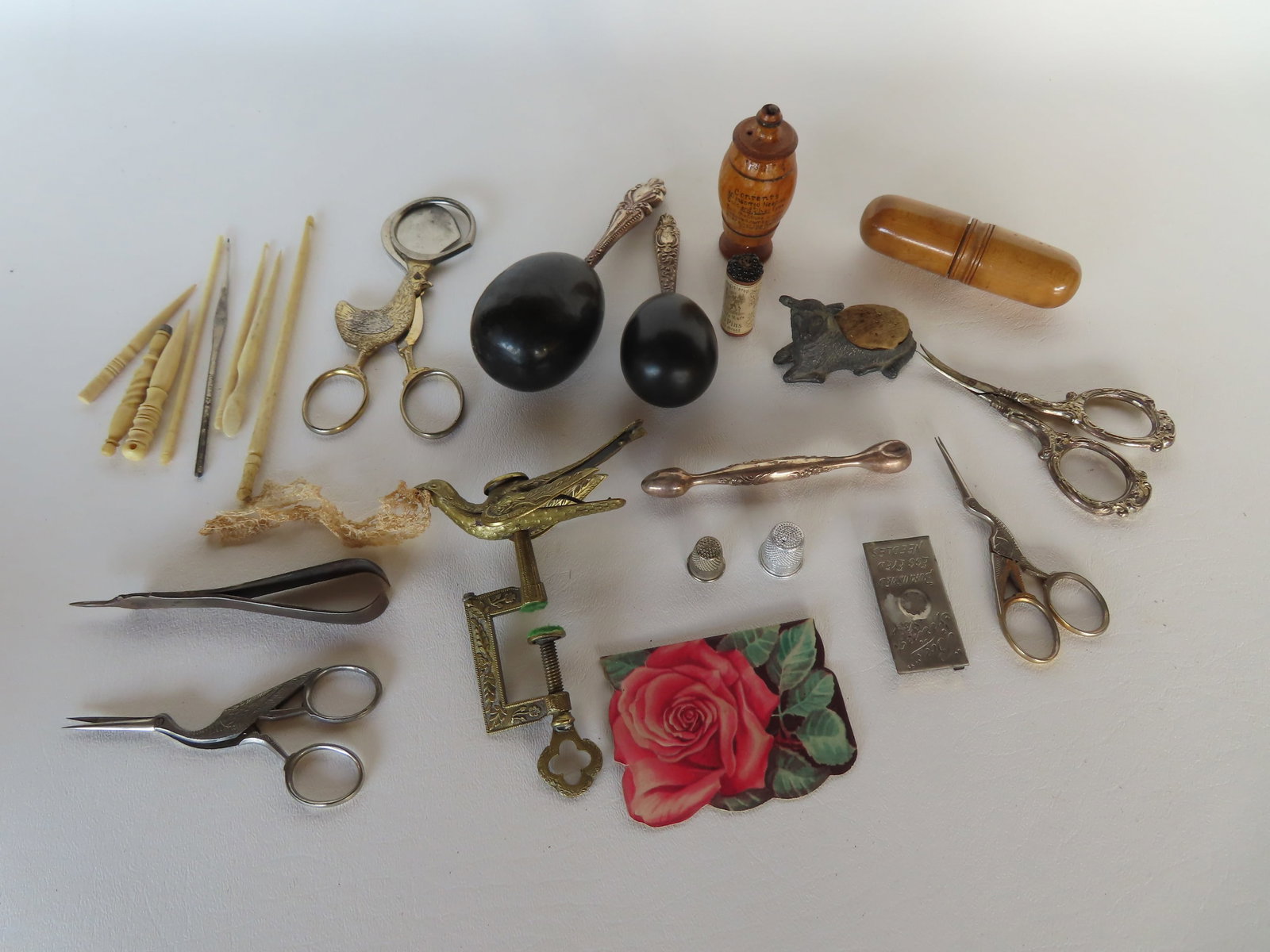 A grouping of sewing related articles including a brass sewing bird (missing lower pin cushion) that: A grouping of sewing related articles including a brass sewing bird (missing lower pin cushion) that was mounted on holder); 2 stork handled scissors, marked Sterling handled scissors, a figural metal