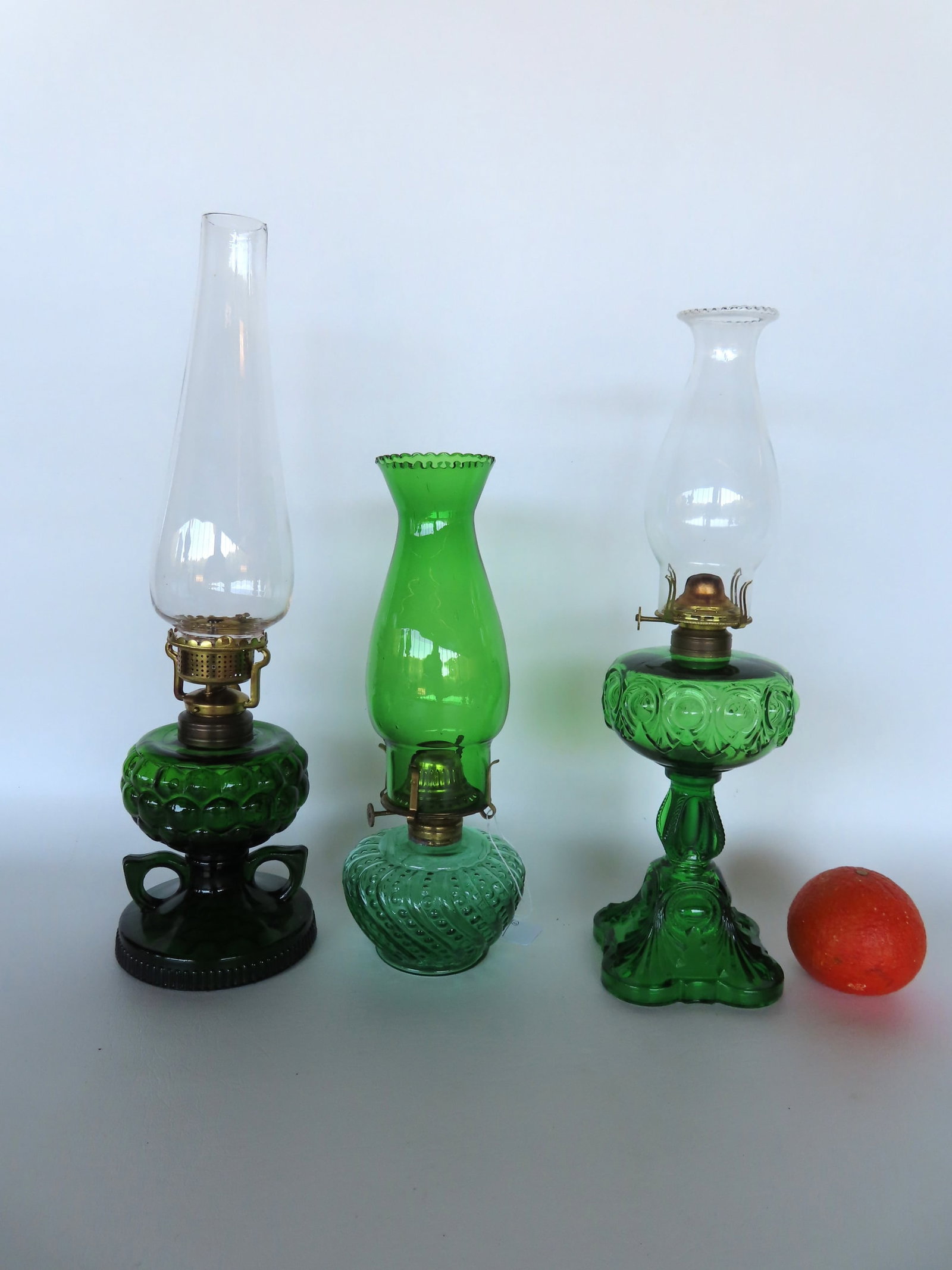 Grouping of 3 pressed glass green oil lamps including one with double fingers and one with green: Grouping of 3 pressed glass green oil lamps including one with double fingers and one with green glass chimney, all 19th century in very good condition. The largest measures 9 1/2"H to top of burner. 