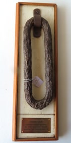 A wall plaque with an attached rusted chain link marked "Chain link found near shore in the Hudson